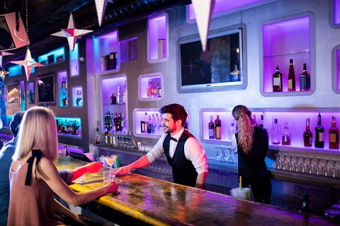 Un barman sirviendo una copa a una señorita
